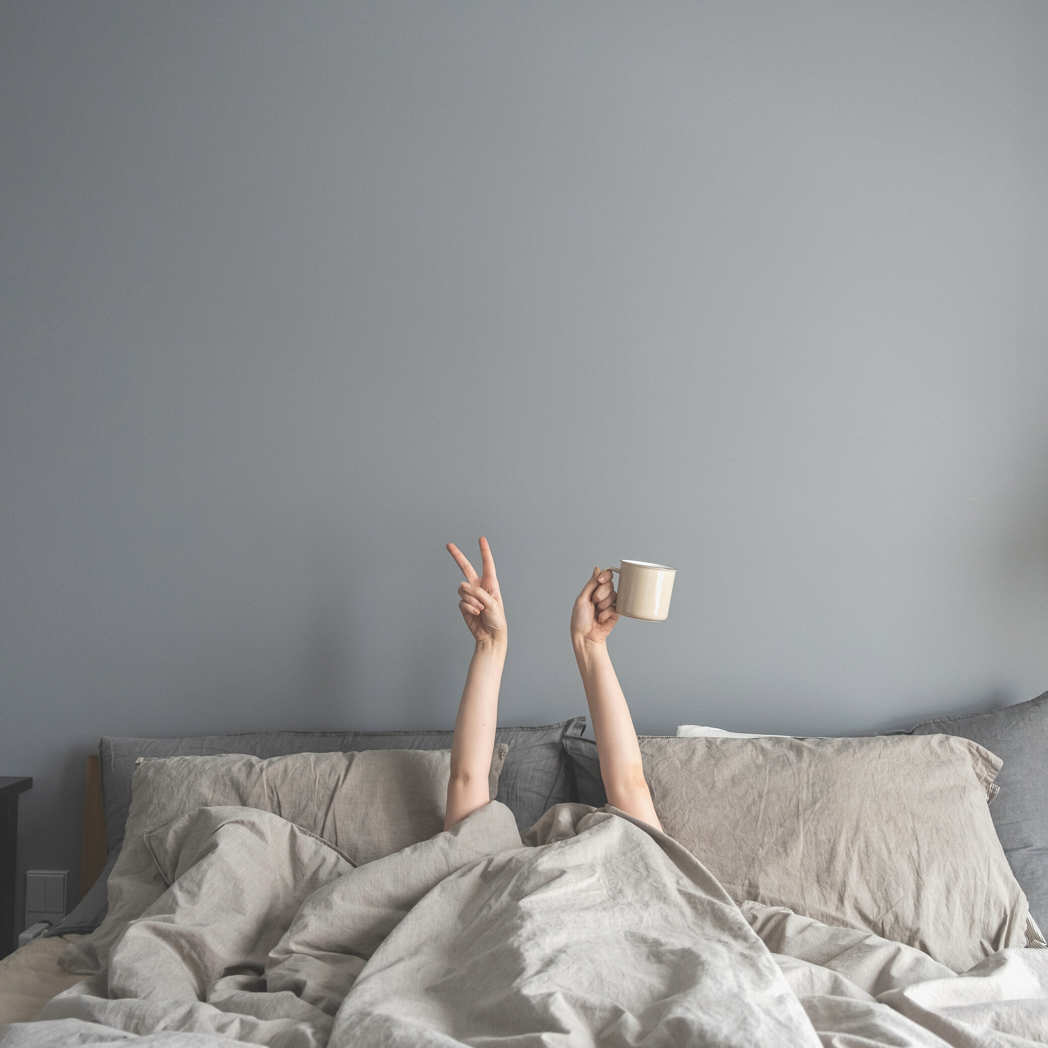 Person Holding a Coffee Mug in Bed