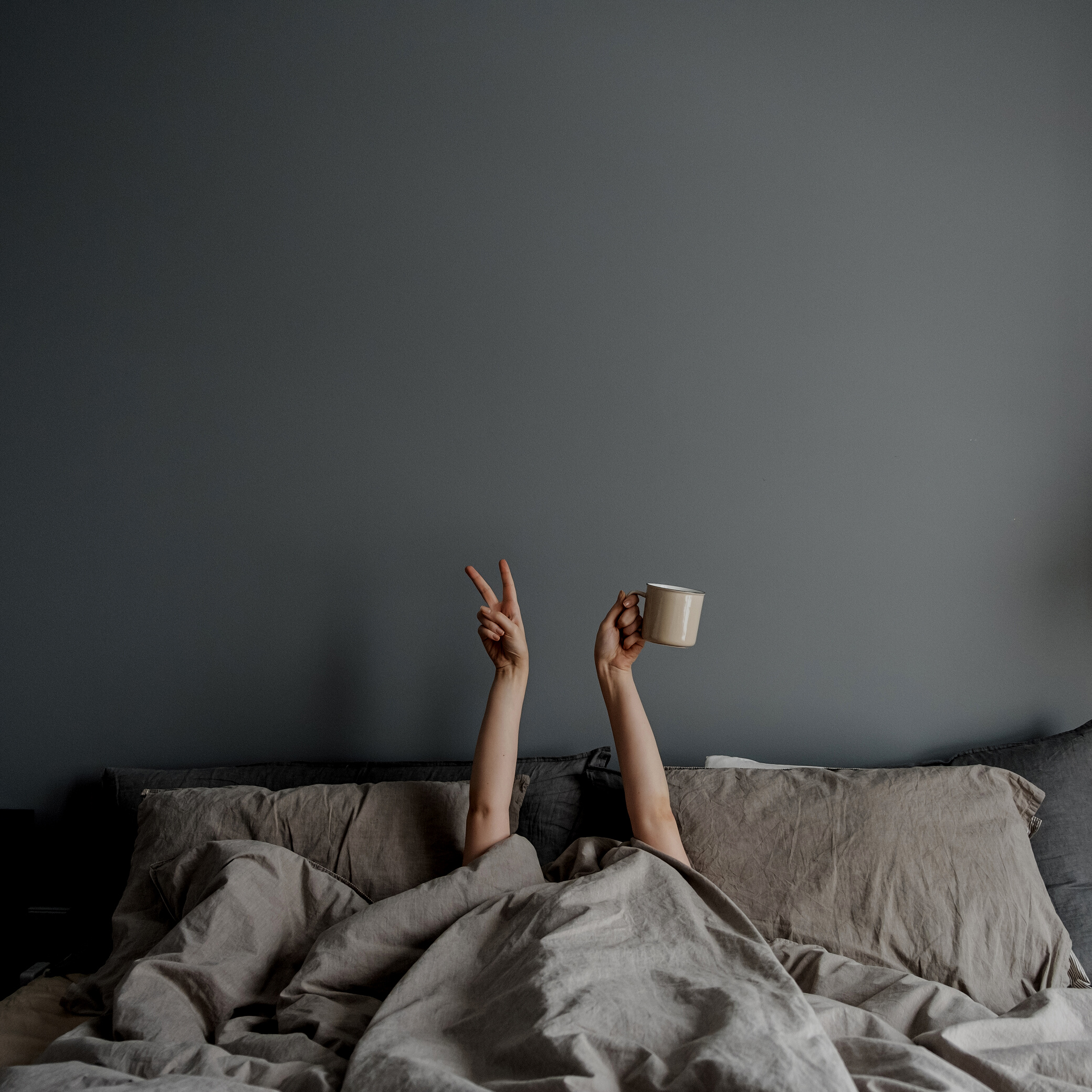 Person Holding a Coffee Mug in Bed